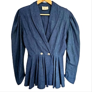 May include: A blue denim jacket with a wrap front and puff sleeves. The jacket has a gold button closure and a label that reads "First Love Vintage".