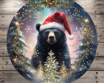 May include: A black bear wearing a red Santa hat with a white trim, surrounded by a wreath of holly and berries. The bear is standing in a snowy forest setting with a small Christmas tree in front of it.
