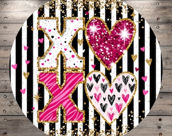 Op de afbeelding: Rond decoratief bord met een zwart-wit gestreepte achtergrond. Het bord toont de letters "XO" in wit en roze zebraprint, samen met twee harten. Eén hart is roze glitter, en de andere heeft zwarte en roze harten. Gouden glitter accenten.