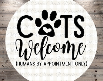 Peut inclure: Un panneau rond avec l'inscription "CATS Welcome" en noir. Le mot "CATS" est au-dessus de "Welcome" et comprend une empreinte de patte avec un cœur. Le texte "(HUMANS BY APPOINTMENT ONLY)" est en dessous.
