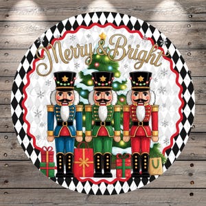 May include: Round Christmas-themed design featuring three toy nutcracker soldiers in blue, green, and red uniforms. The words "Merry & Bright" are in gold script above a Christmas tree. The border is black and white diamonds with a red trim.
