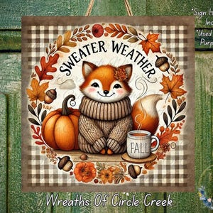 May include: A square sign with a fox illustration, surrounded by fall foliage and the words "Sweater Weather." The fox wears a sweater and sits near a pumpkin and a mug that says "FALL." The background has a plaid pattern.