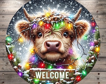 May include: Round wooden sign featuring a Highland cow decorated with colorful Christmas lights and a "WELCOME" sign. The cow has brown fur and is surrounded by snowy pine branches and falling snow. The sign is set against a wood-grain background.