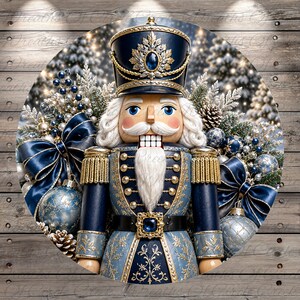 May include: A circular decorative sign featuring a nutcracker in a navy blue and gold uniform with a matching hat, surrounded by blue and silver Christmas ornaments, pine branches, pinecones, and large navy blue satin bows on a wood background.