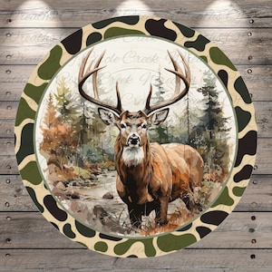 May include: Round decorative sign featuring a majestic deer in a forest scene. The deer has large antlers and is surrounded by trees and a river. The sign has a camouflage border and the text "Circle Creek Nature" is visible.