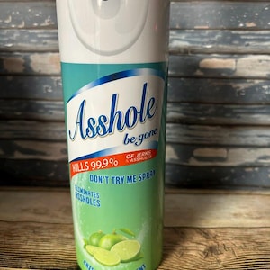 Puede incluir: Un vaso cilíndrico con un diseño en blanco y verde claro que recuerda a un aerosol. La etiqueta dice Asshole be gone, Kills 99.9% of jerks & assholes, Don't try me spray, Eliminates assholes y Crisp fuch off scent, con gráficos de limas.