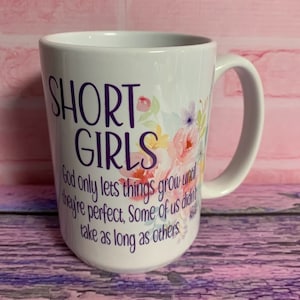 Könnte beinhalten: Eine weiße Keramik-Kaffeetasse mit einem violetten Blumendesign und dem Text "SHORT GIRLS God only lets things grow until they're perfect. Some of us didn't take as long as others."