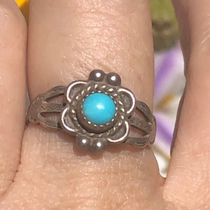 May include: A silver ring with a turquoise stone set in a flower design.