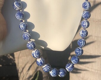 May include: A white and blue porcelain necklace with round beads featuring a repeating Chinese symbol design.