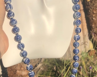 May include: A white and blue porcelain bead necklace with Chinese characters. The beads are round and have a glossy finish.
