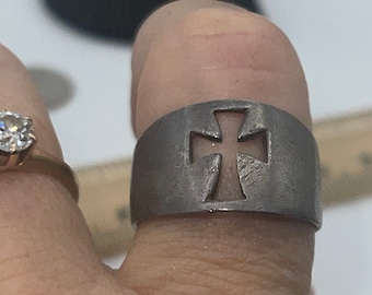 May include: A silver ring with a cut-out cross design. The ring is wide and has a textured finish.
