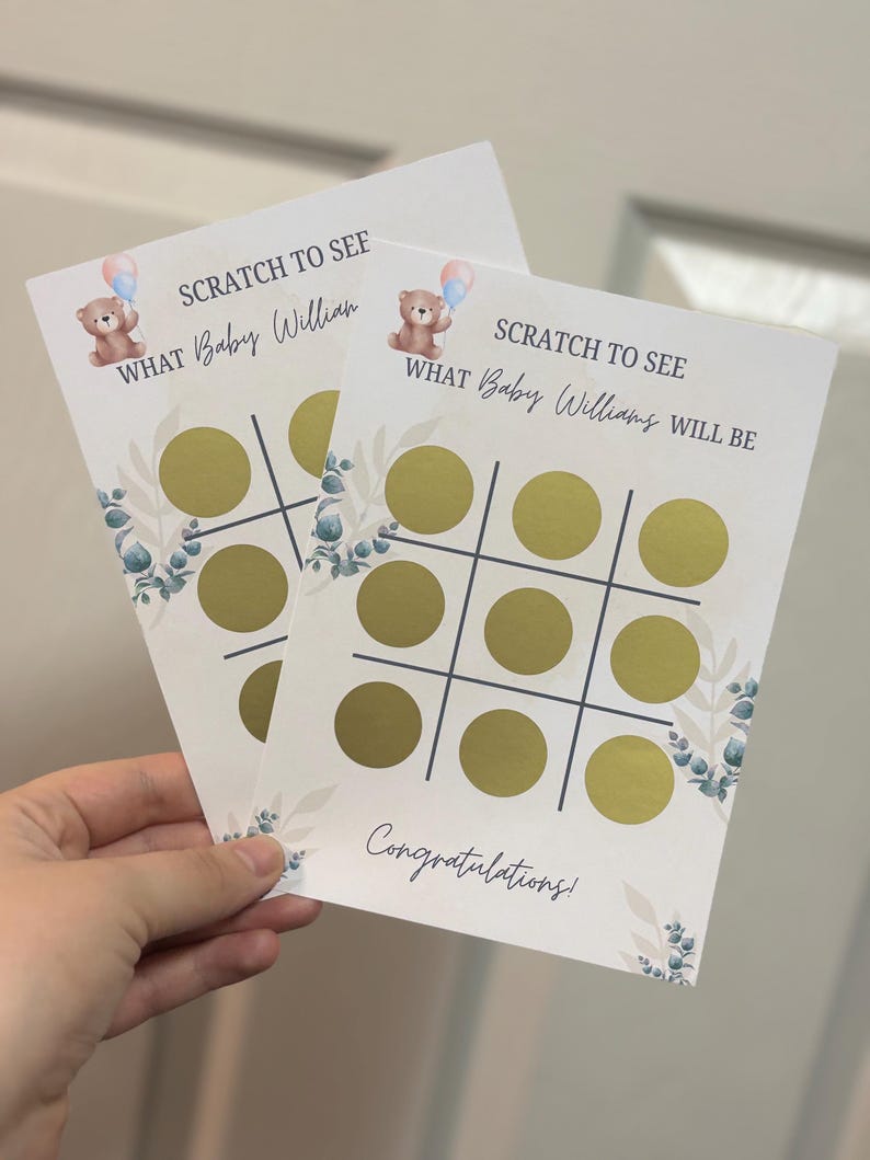 May include: Two baby shower scratch-off cards with a tic-tac-toe grid and gold circles. The cards feature a teddy bear with balloons, floral accents, and the text "SCRATCH TO SEE WHAT Baby William/Williams WILL BE" and "Congratulations!".