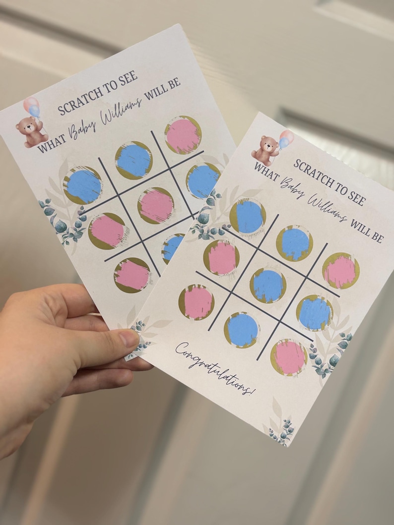 May include: Two baby shower scratch-off cards with a tic-tac-toe design. The cards have blue and pink circles, with text that reads "SCRATCH TO SEE WHAT Baby Williams WILL BE." A teddy bear graphic is at the top.