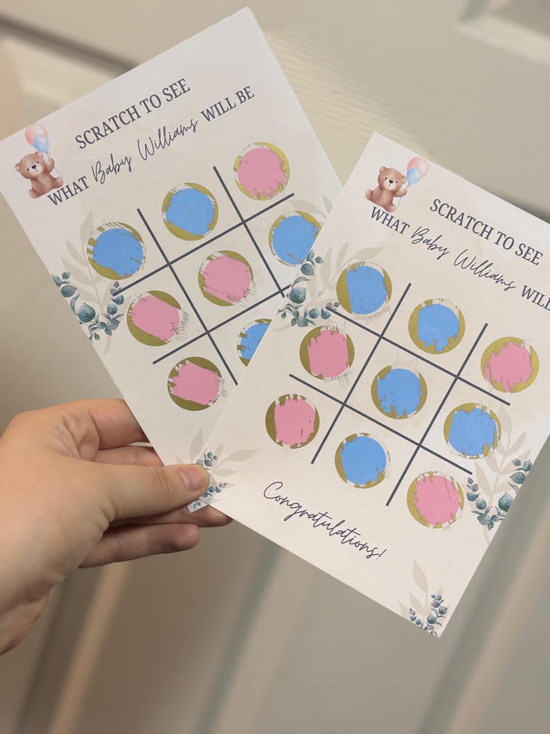 May include: Two baby shower scratch-off cards with a tic-tac-toe grid featuring pink and blue circles. The cards have text that reads "SCRATCH TO SEE WHAT Baby Williams WILL BE" and "Congratulations!" A teddy bear graphic is also present.