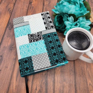 May include: A teal, black, white, and gray patchwork fabric journal cover with a black ribbon bookmark.