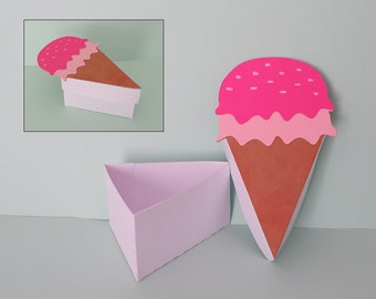 May include: A pink and brown ice cream cone shaped box with a lid. The box is made of paper and is decorated with pink and white sprinkles.