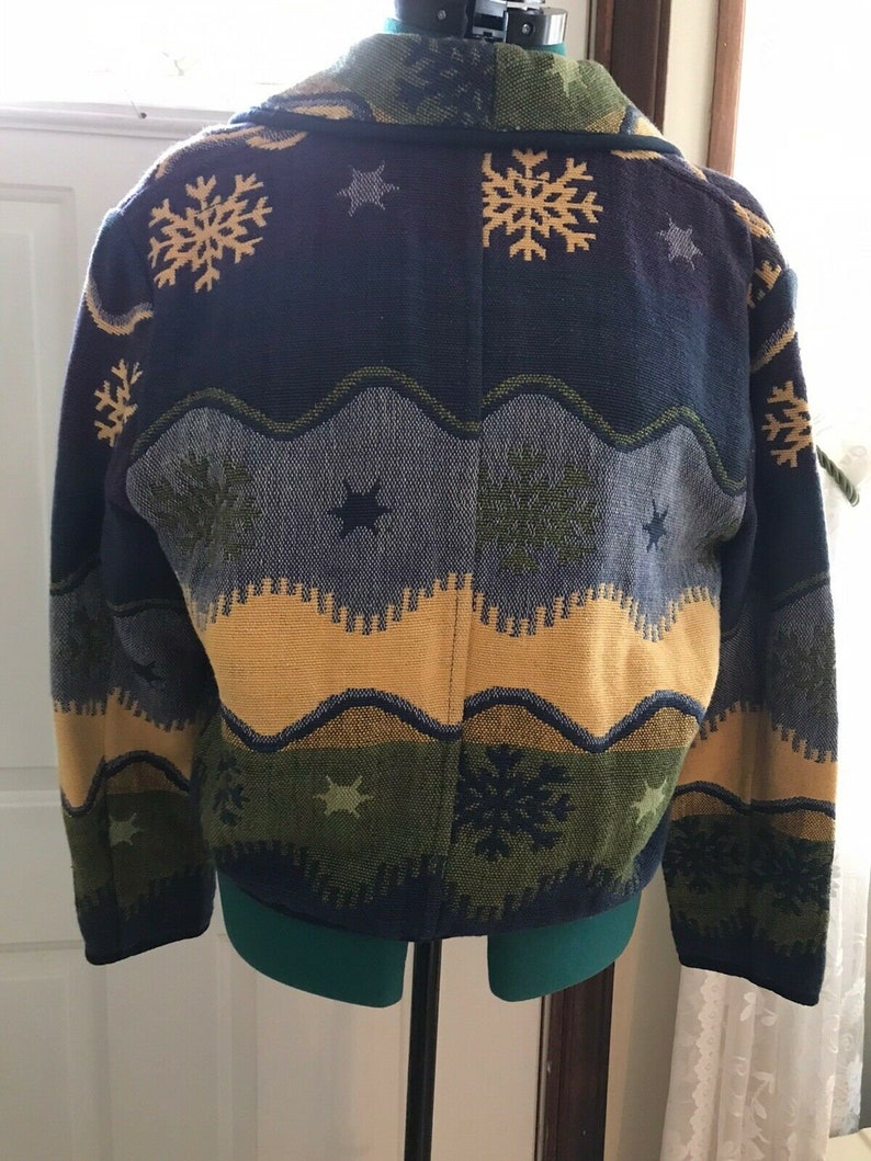 May include: A blue, green, yellow, and gray patterned cardigan with a snowflake and star design.