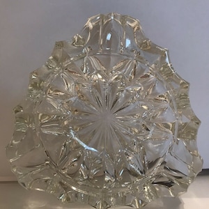 Peut inclure: Un cendrier en verre transparent avec un motif en étoile et un bord festonné.