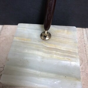May include: A brown pen holder with a gold metal base sits on a white and gray marble pen stand.