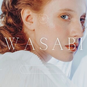 May include: A close-up of a woman's face with red hair, looking over her shoulder. The text "WASABI" is in white letters against a light blue background. The text "VIDEO FILTERS" is in a white button.