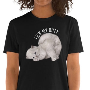 May include: A black t-shirt with a white kitten curled up on its back. The text "LICK MY BUTT" is printed above the kitten.