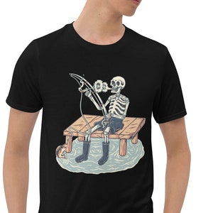 May include: Black t-shirt featuring a graphic of a skeleton fishing from a wooden jetty. The skeleton is wearing a blue hat and holding a fishing rod.