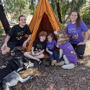 Family with their dogs camping and wearing matching dog and owner shirts