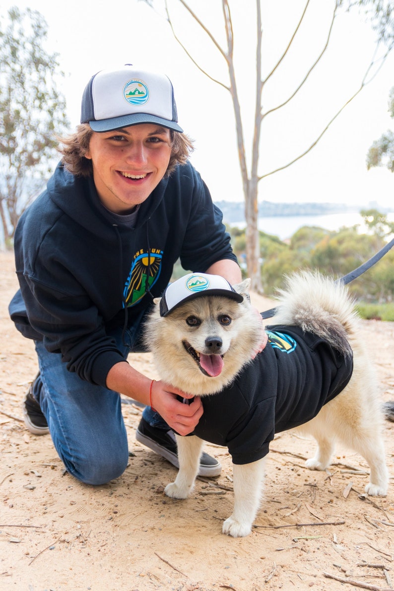 A man and his dog wearing matching dog and owner trucker hats from PupLids.
