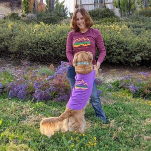 Woman getting the paw from her dog and wearing vibrant colored matching hiking shirts