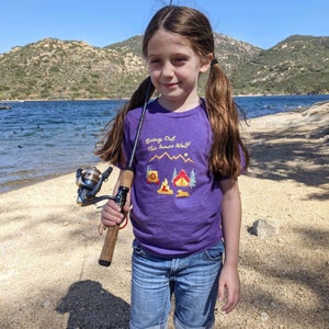 Young girl going fishing and wearing a purple dog themed camping t-shirt