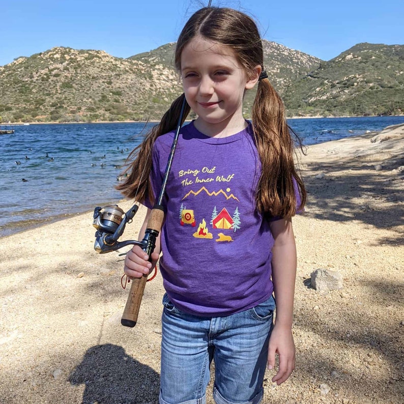 Young girl going fishing and wearing a purple dog themed camping t-shirt