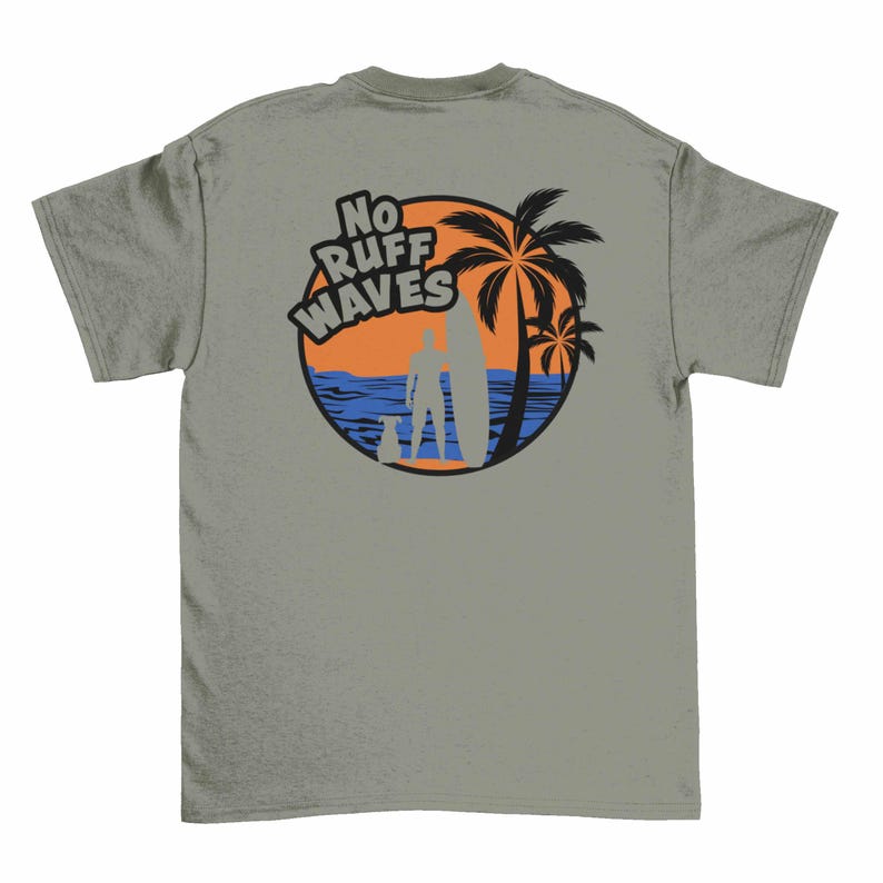 May include: A sage green t-shirt featuring a circular graphic on the back. The design shows a silhouette of a person with a surfboard and a dog standing on a beach with palm trees, blue ocean waves, and an orange sky. The text reads NO RUFF WAVES.