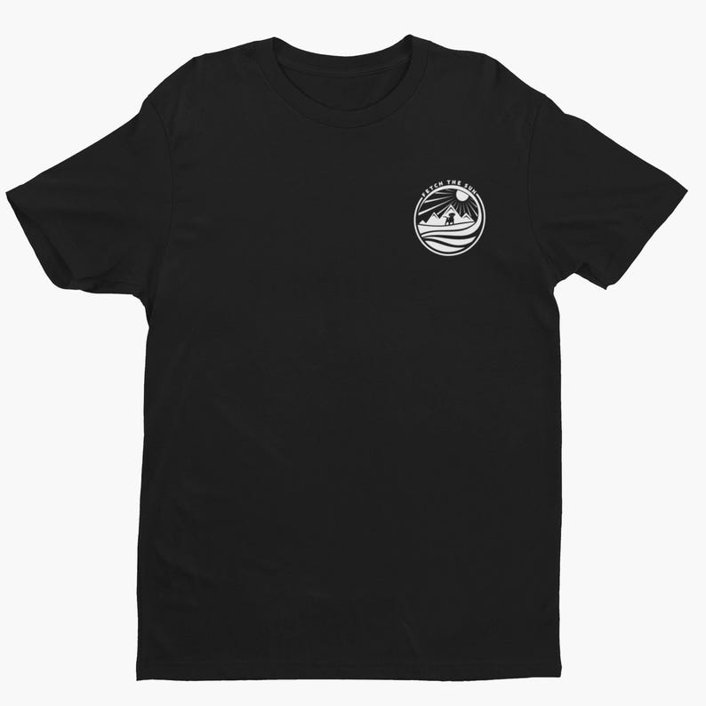 May include: A black short-sleeve t-shirt featuring a circular white graphic on the upper left chest. The graphic depicts a sun, mountains, and a dog silhouette with the text "FETCH THE SUN" arched along the top edge of the circular design.