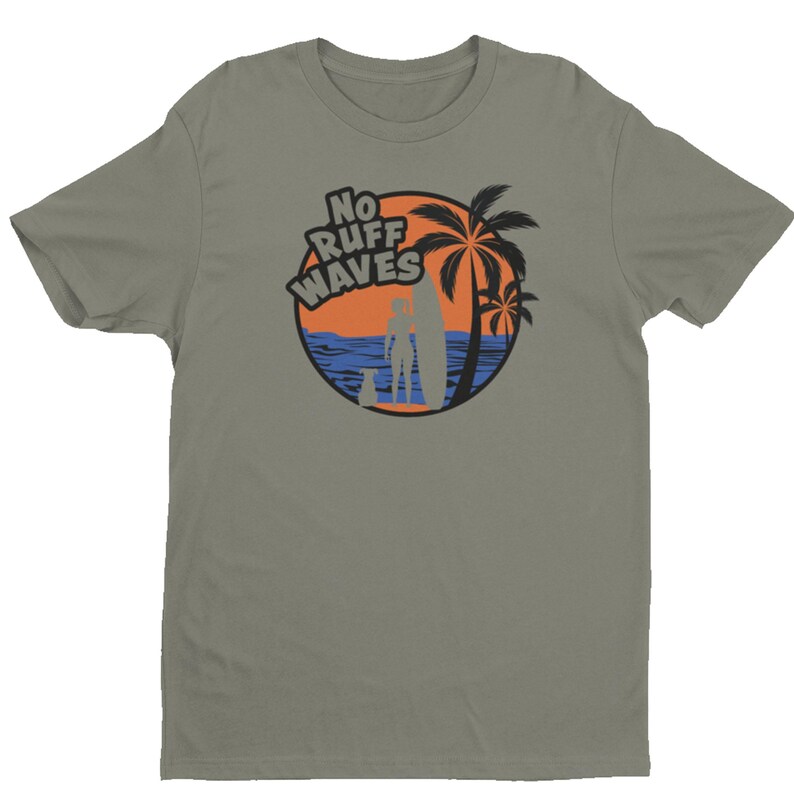 May include: A sage green short-sleeved t-shirt featuring a circular graphic on the chest. The design depicts a beach scene with a palm tree, a surfboard, a person, and a dog, with the text NO RUFF WAVES printed in bold black letters above.