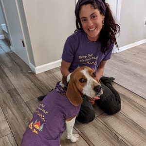 Woman and her dog posing in matching purple dog shirts