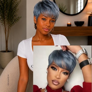 May include: A short, layered pixie cut wig in a cool-toned dusty blue color. The hair features a textured, piecey finish with soft bangs that frame the forehead. The style is uniform in length around the sides and back, creating a sleek, modern look.