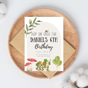 May include: A birthday invitation with the text "HOP ON OVER FOR DANIEL'S 4TH Birthday". The invitation features illustrations of mushrooms, frogs, and balloons. The invitation is on a white background, with a brown envelope and wooden plate.