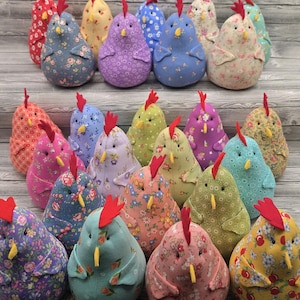 May include: A collection of twenty-five plush fabric chickens in various colors and floral patterns. Each stuffed chicken features a bright red felt comb, a small yellow felt beak, and two black bead eyes, arranged in rows.