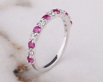 May include: A delicate eternity band featuring alternating pink sapphires and white diamonds set in a polished white gold band.