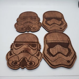 May include: Set of four brown wooden coasters featuring a laser-engraved design of a Star Wars Stormtrooper helmet.