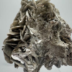 May include: A large, gray, rock-like specimen of mica with a clear, light blue aquamarine crystal on top.