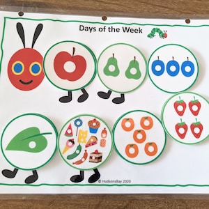 May include: A colorful educational chart featuring a caterpillar with different colored circles, each containing a different number of objects. The chart is titled "Days of the Week" and includes the text "&copy; HudsonsBay 2020".