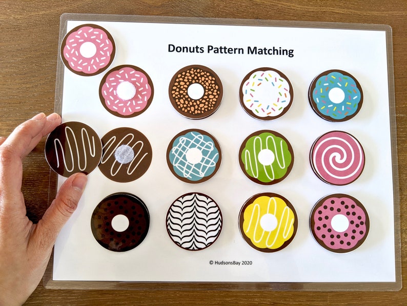 May include: A set of 12 donut-shaped felt pieces with various patterns, including sprinkles, chocolate drizzle, and swirls. The pieces are designed for a matching game, with the text "Donuts Pattern Matching" at the top of the white background.