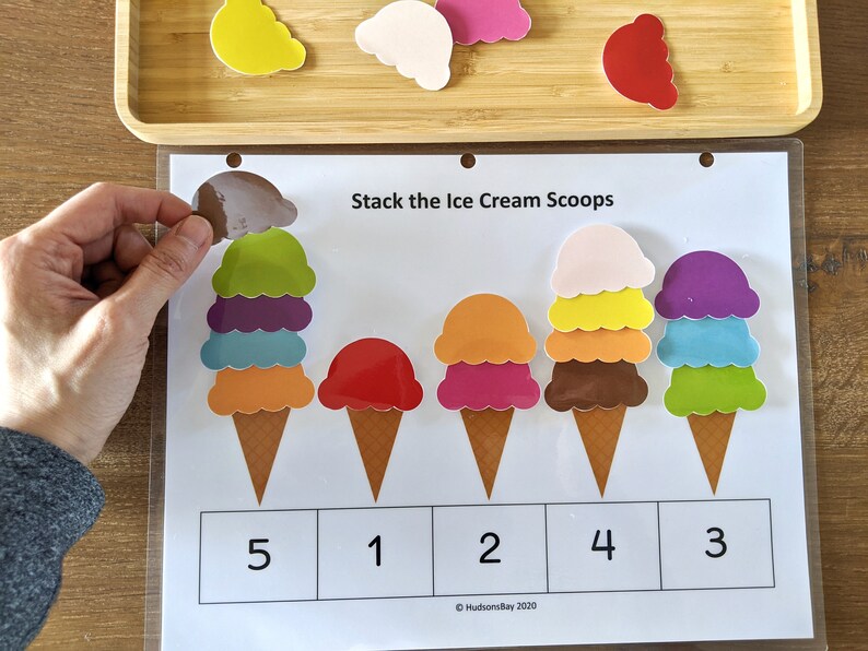 May include: A learning activity for kids featuring five ice cream cones with different colored scoops. The cones are arranged in a row and numbered 1 through 5. The text "Stack the Ice Cream Scoops" is at the top of the page.