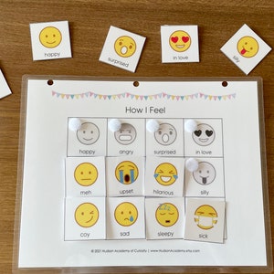 Pode incluir: Um quadro branco laminado com uma grade de 12 quadrados. Cada quadrado cont&eacute;m um rosto de desenho animado amarelo com uma express&atilde;o diferente. As express&otilde;es incluem feliz, com raiva, surpreso, apaixonado, meh, chateado, hil&aacute;rio, bobo, t&iacute;mido, triste, com sono e doente. As palavras "Como me sinto" s&atilde;o impressas no topo do quadro.