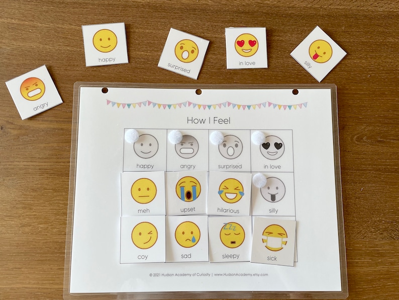 Pode incluir: Um quadro branco laminado com uma grade de 12 quadrados. Cada quadrado cont&eacute;m um rosto de desenho animado amarelo com uma express&atilde;o diferente. As express&otilde;es incluem feliz, com raiva, surpreso, apaixonado, meh, chateado, hil&aacute;rio, bobo, t&iacute;mido, triste, com sono e doente. As palavras "Como me sinto" s&atilde;o impressas no topo do quadro.