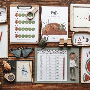 May include: A collection of educational resources for children, featuring insect-themed flashcards, a counting worksheet, and a maths workbook. The items are arranged on a wooden surface.