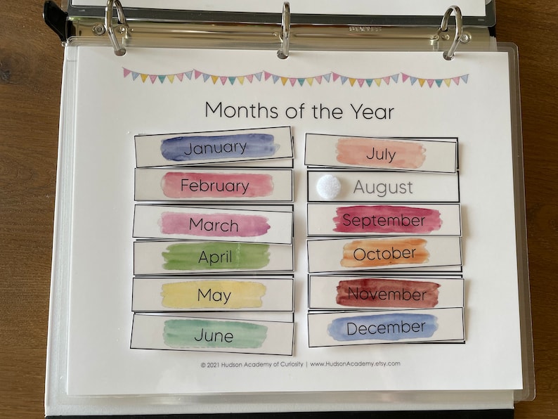 Pode incluir: Uma folha de trabalho imprim&iacute;vel com nomes de meses pintados em aquarela em uma pasta. Os meses do ano est&atilde;o listados em ordem de janeiro a dezembro. A folha de trabalho &eacute; intitulada "Meses do ano".