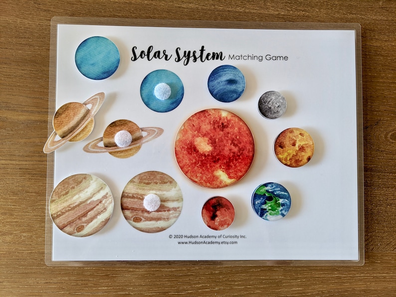 May include: A colorful solar system matching game with planets and a sun. The planets are illustrated with watercolor and have a white felt circle on the back for matching.