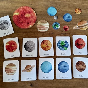 May include: A set of 10 watercolor cards featuring the planets of our solar system, including the sun, moon, Mercury, Venus, Earth, Mars, Jupiter, Saturn, Uranus, Neptune, and Pluto. Each card has a watercolor illustration of the planet and its name printed below.